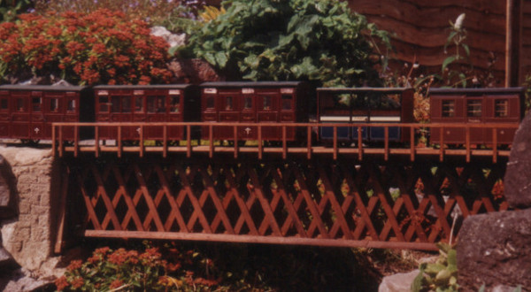 Tan-y-Manod style wooden bridge across the garden path. Colin Binnie`s garden railway in Somerset